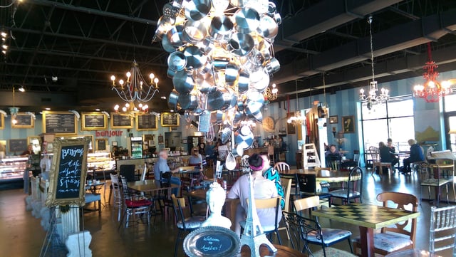 Inside of Amelie's Carmel Commons with a large hanging light sculpture made out of stainless steel cooking equipment. 