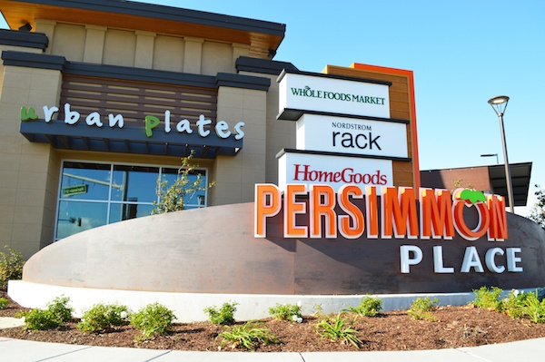 Persimmon Place signage with various store logos attached, and an Urban Plates storefront in the background. 