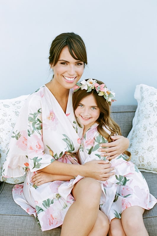 woman in floral robe hugging young girl in same floral robe and flower crown