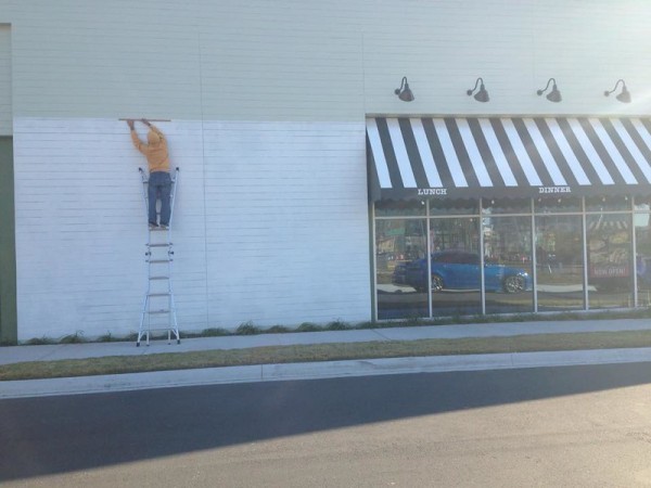 Artist painting side of storefront