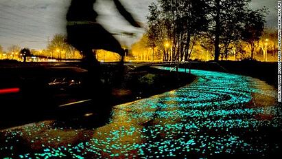 Illuminated bike path at night with blurred biker streaking by