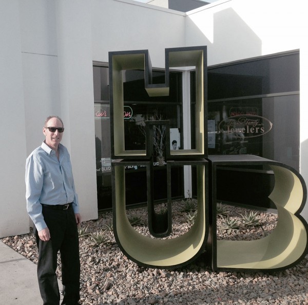 Gregg Sadowsky standing outside in front of a large HUB logo