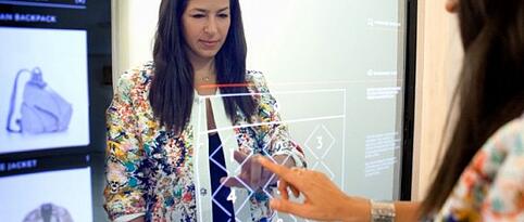 Woman touching a screen in a fitting room that is technologically advanced