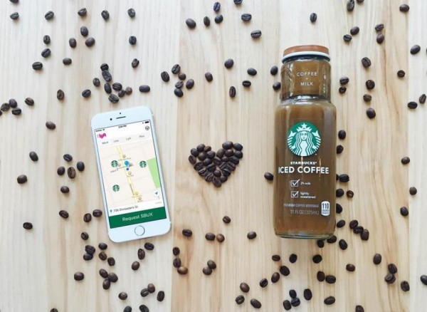 Overhead view on an iPhone, a bottle of cold coffee from starbucks, and coffee beans shaped like a heart, all on a wooden table