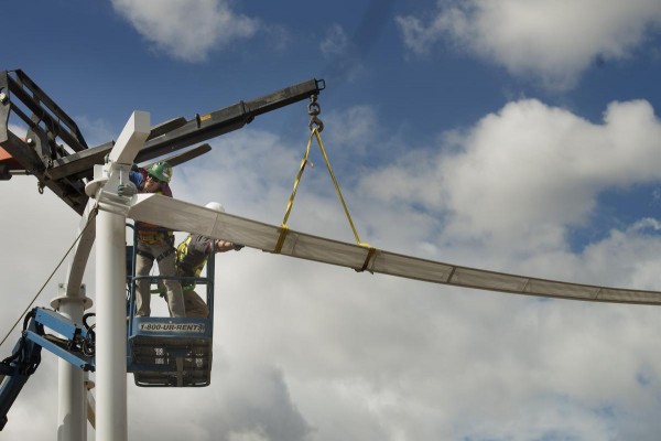 Two construction workers high up in a lift, working on the art installation