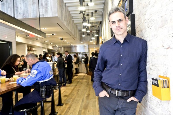 Brett Schulamn leaning against a wall inside of a restaurant