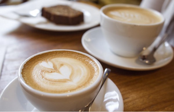 Two lattes on saucers with heart designs made out of the foam