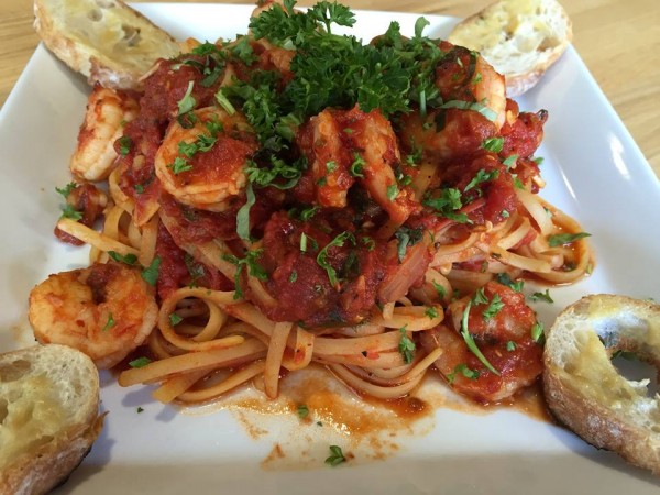 Pasta dish of linguini with shrimp and marinara sauce with fresh parsley and garlic bread