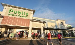 Publix food and pharmacy store front with people lined up outside to get in
