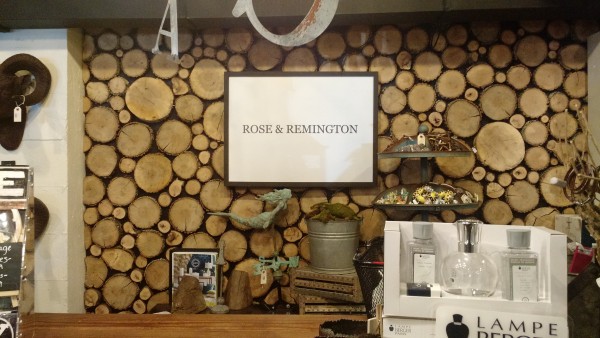 Inside Rose and Remington store with a large picture of stacked logs on a wall behind a counter