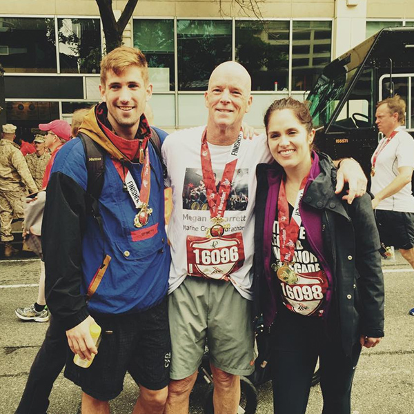 Three runners posing for a photo together after a race, wearing their medals at the finish line