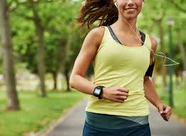 woman running outside with smart watch and headphones