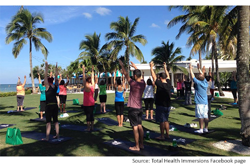 group of people doing yoga outside in florida near the water