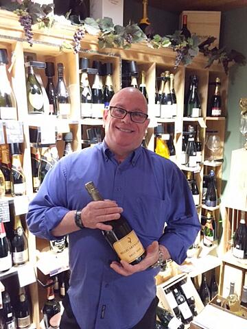 Tommy Garland inside QFC holding a bottle of champagne. 
