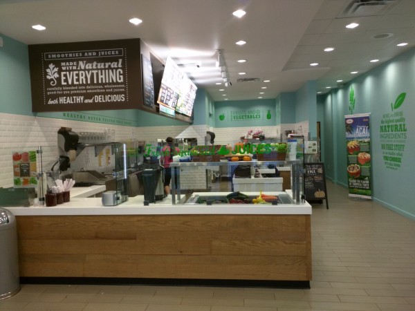 Inside of a local juice bar with teal walls and wood counter. 