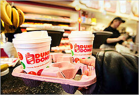 Two holiday Dunkin Donuts coffee cups in a carryout container from within the Dunkin location