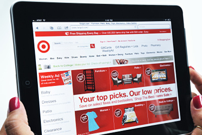 woman holding a tablet that shows Target's website. 