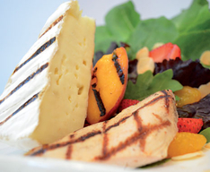 grilled cheese and fruit on a bed of leafy greens