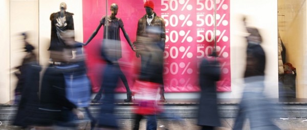 Blurred shoppers walking by a clothing storefront window