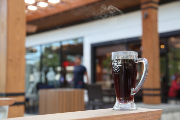 Image of hot brewed coffee in a clear glass mug on a ledge in front of a store