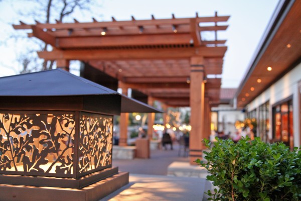 Image of a walkway with plank canopies near a row of retailers