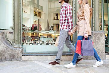 couple holding hands and shopping together with shopping bags in hand