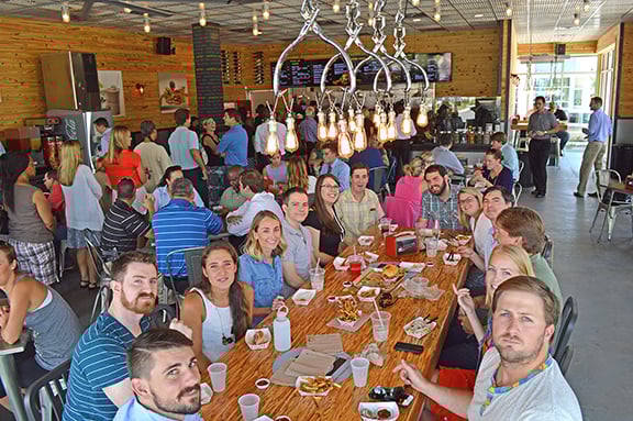 Many people eating at a long wooden table