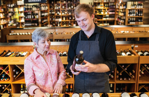 Employee helping a female customer select wine. 