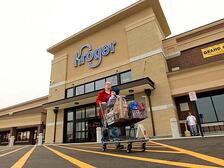 Kroger storefront with woman pushing a full shopping cart with a child in the cart