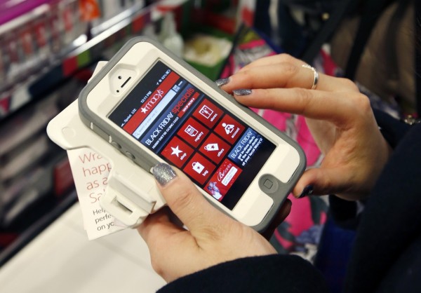 A woman holding an iphone while looking at  Macy's mobile site. 