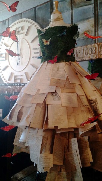 inside rose and remington with a mannequin on display showcasing a dress made from moss, butterflies and pages from books