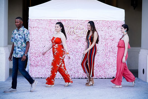 3 women and 1 man modeling in front of pink flower wall for The Grove