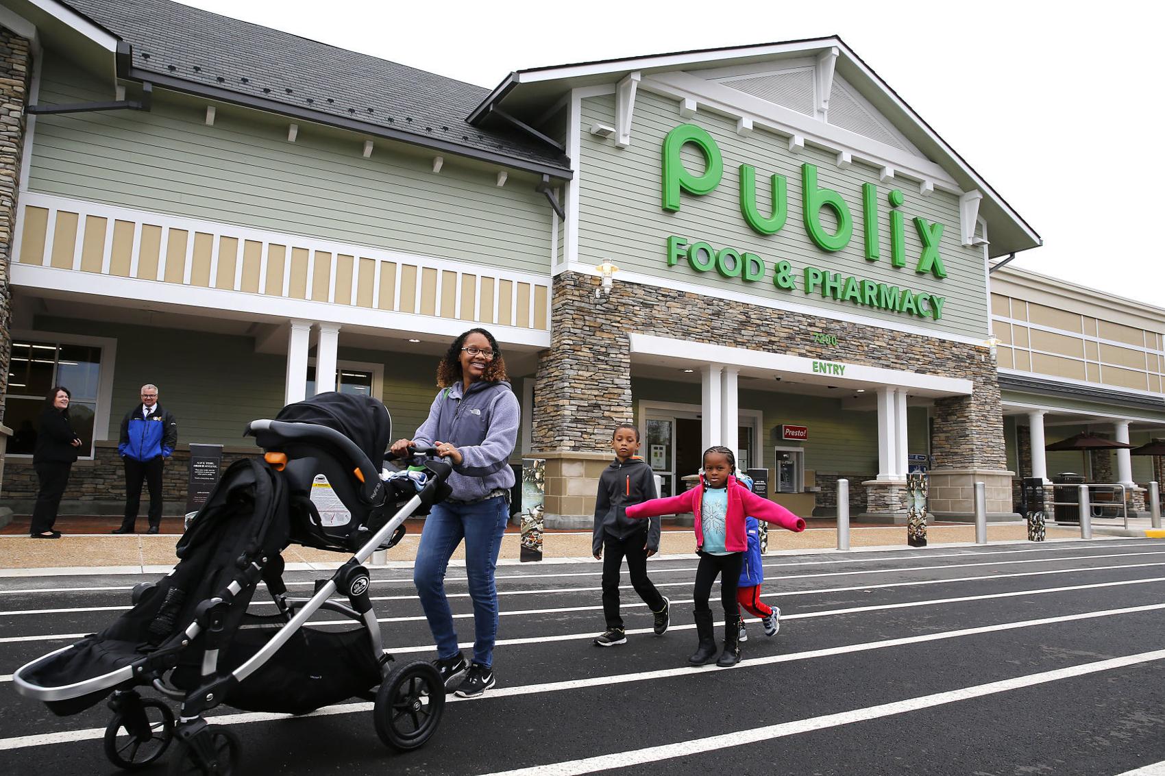 Mother pushing a stroller with kids behind her, leaving a Publix food and pharmacy store