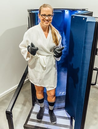 Woman, and writer of story, in a bathrobe posing in front of a cryogenic chamber.  