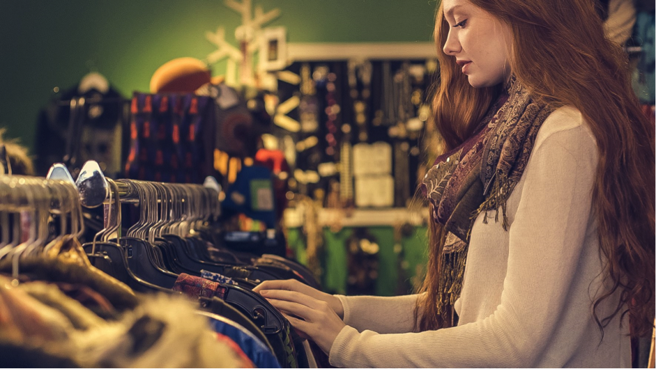 young woman shopping in store looking at rack of clothing