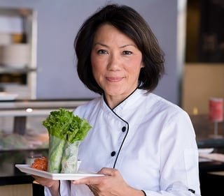 Chef Thoa holding a dish of leafy greens. 