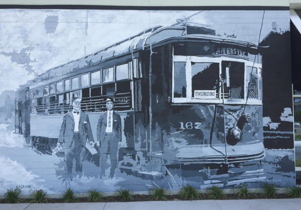 Black and white mural of two men standing next to an old Riverside trolley