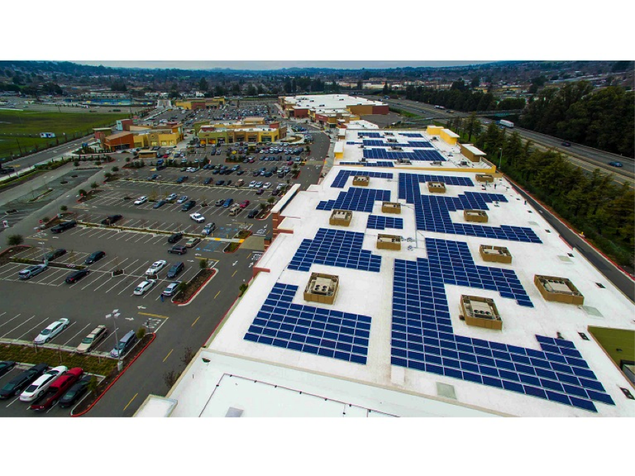 aerial view of solar panels next to a large parking lot. 