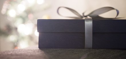 A purple gift box with a silver bow tied around it. 