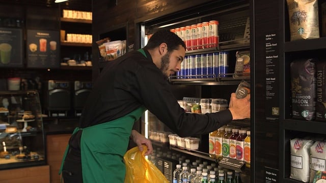 Starbucks employee stocking shelves of store refrigerator