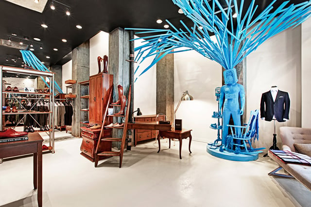 inside of Public Factory store shoes on display and a bright blue sculpture of a man with an old-fashioned radio for a head and long tubes coming out of it. 