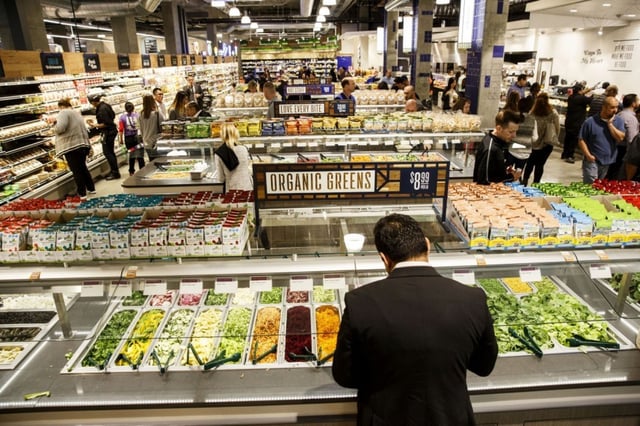 Man standing at a salad bar inside Whole Foods. 