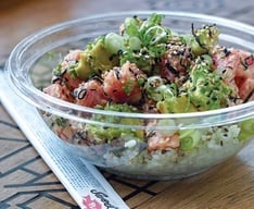 A poke bowl and unopened chopsticks on a table.