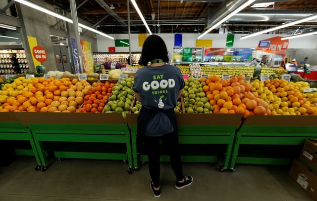 Employee looking at pears in fruit section of 365 by Whole Foods