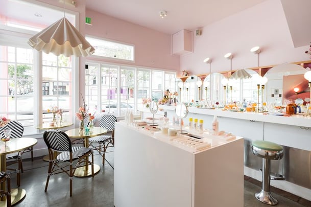 Inside Glossier's pop-up shop, with seating and tables. 