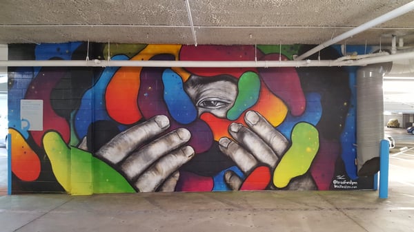 Mural of two hands an eye behind organic colored shapes