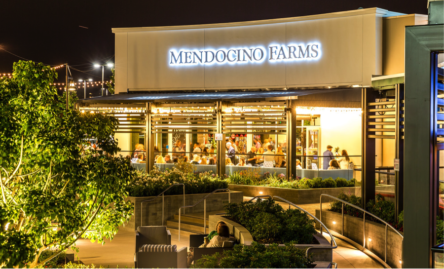 Mendocinio Farms storefront next to outside seating area at night.