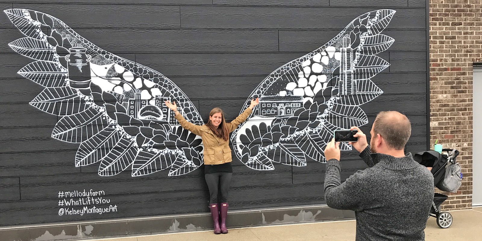 Woman posing in front of a Kelsey Montague Wings Mural