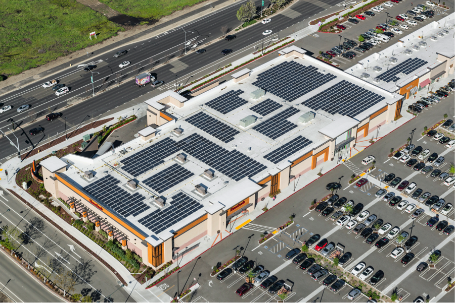 Company building with solar panels on roof surrounded by a large parking lot. 