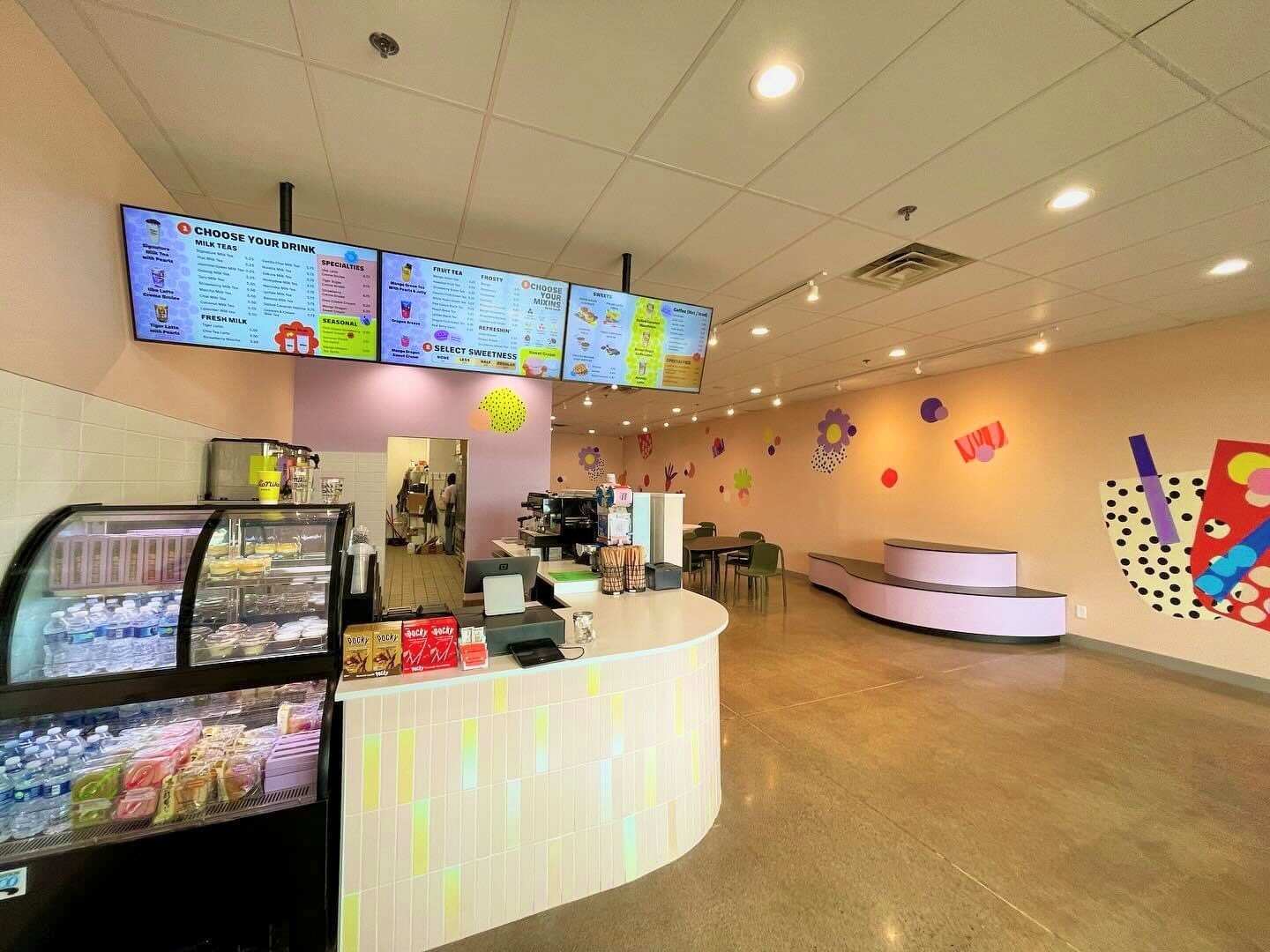 Entrance, menu, and front desk of Niko Niko Boba, colorful murals decorate the back wall